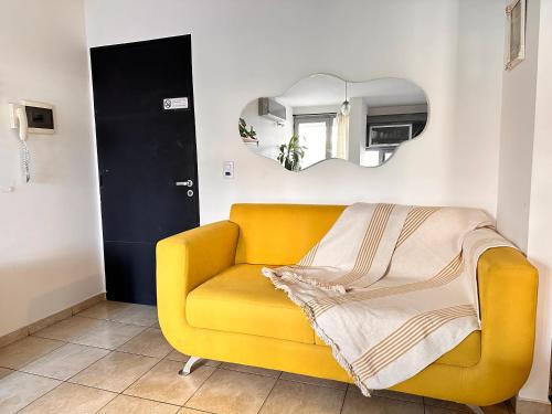 a yellow couch in a room with a mirror at Departamento Ecofriendly excelente ubicación in Cordoba