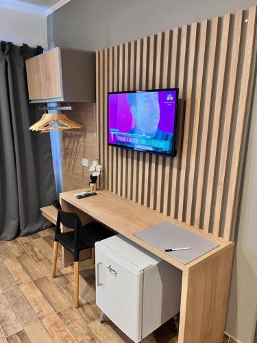 een kamer met een bureau en een tv aan de muur bij Ayres Apart Hotel in Federal