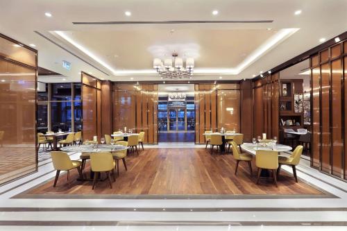 a dining room with tables and chairs and a chandelier at DoubleTree By Hilton Skopje in Skopje