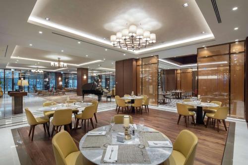 un restaurante con mesas, sillas y un piano en DoubleTree By Hilton Skopje, en Skopje