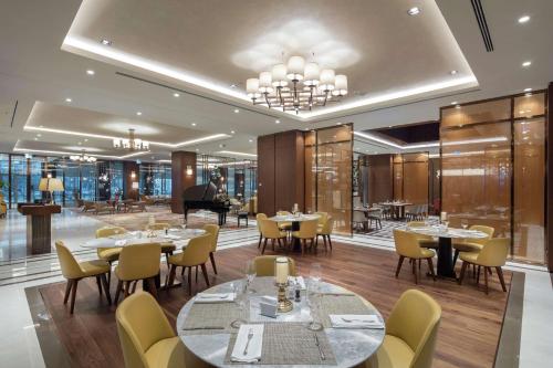 un ristorante con tavoli, sedie e pianoforte di DoubleTree By Hilton Skopje a Skopje