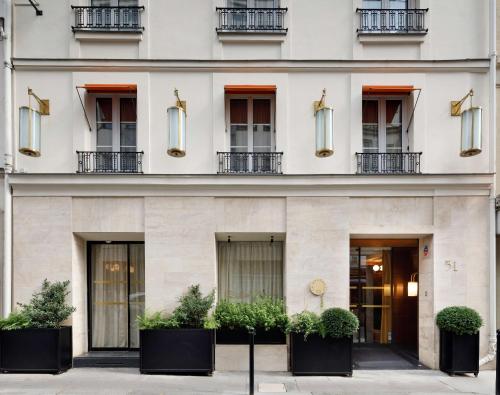 a facade of a white building with potted plants at Le Belgrand Hotel Paris Champs Elysees, Tapestry By Hilton in Paris