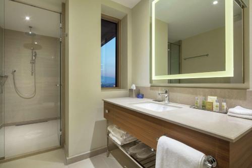a bathroom with a sink and a shower and a mirror at DoubleTree By Hilton Skopje in Skopje