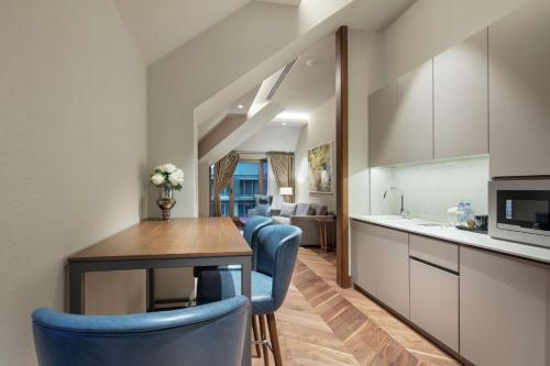 a kitchen and dining room with a table and blue chairs at DoubleTree By Hilton Skopje in Skopje