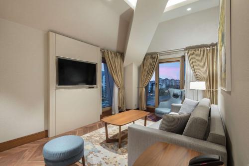 a living room with a couch and a tv at DoubleTree By Hilton Skopje in Skopje