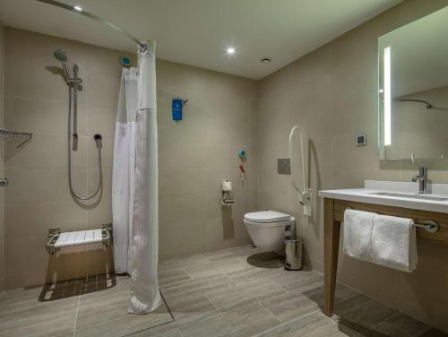 a bathroom with a shower and a toilet and a sink at Hampton By Hilton Kahramanmaras in Kahramanmaraş