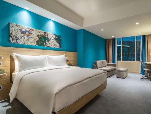 カフラマンマラシュにあるHampton By Hilton Kahramanmarasの青い壁のベッドルーム1室(大型ベッド1台付)