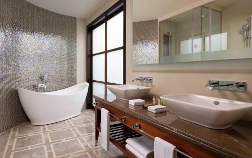 ein Badezimmer mit zwei Waschbecken, einer Badewanne und einem Spiegel in der Unterkunft Hilton Dushanbe in Duschanbe