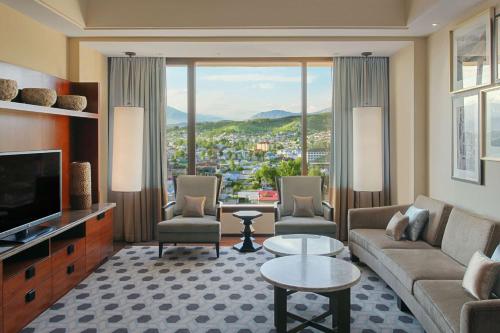 a living room with a couch and chairs and a television at Hilton Dushanbe in Dushanbe