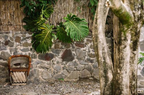 a stone wall with a rattan chair and plants at Anzan Atitlan in San Marcos La Laguna