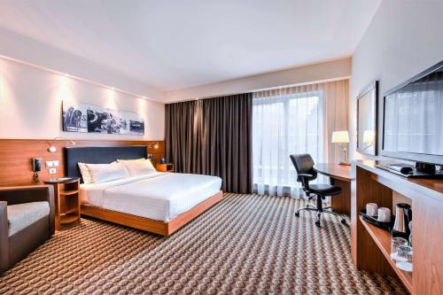 a hotel room with a bed and a desk and a television at Hampton by Hilton Warsaw Airport in Warsaw