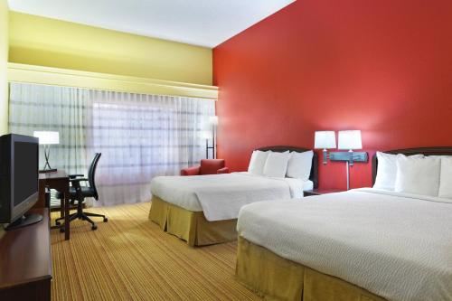 a hotel room with two beds and a desk and a tv at Courtyard Chesapeake Greenbrier in Chesapeake