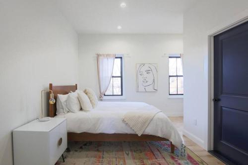 a white bedroom with a large bed and windows at Large 2 BDR With Deck Hosted By StayRafa in Philadelphia