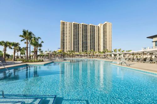 a large swimming pool in front of a large building at Embassy Suites by Hilton Myrtle Beach Oceanfront Resort in Myrtle Beach