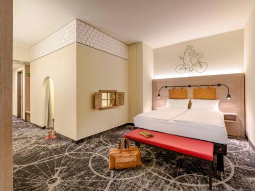una camera d'albergo con letto e panca rossa di ibis Styles Magdeburg a Magdeburgo