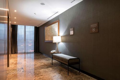 a room with a bench and a lamp on a wall at Hilton Garden Inn Chihuahua in Chihuahua
