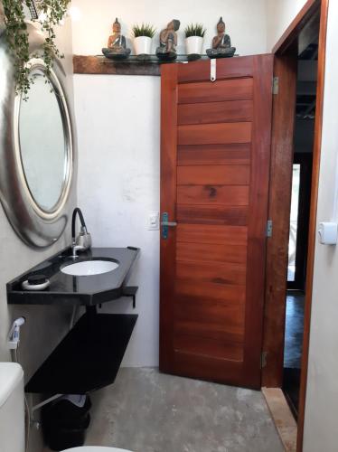 uma casa de banho com um lavatório e uma porta de madeira em Kite & Sol Beach House Taiba em Taíba