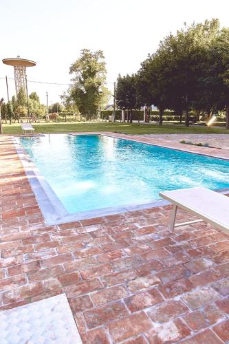 a large blue swimming pool with a bench next to it at Agriturismo La Foscarina in Vescovana