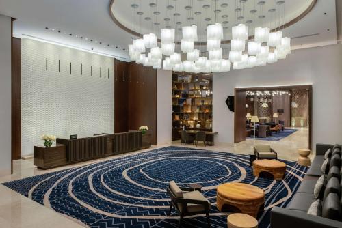 a lobby with a large blue rug and a chandelier at Hilton Guadalajara Midtown in Guadalajara