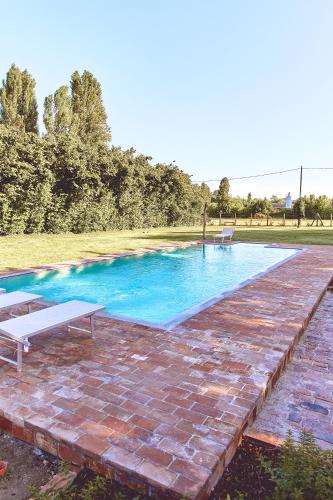 a swimming pool with two chairs and a brick patio at Agriturismo La Foscarina in Vescovana