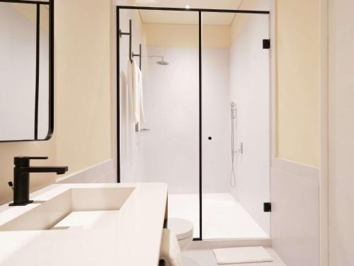 a white bathroom with a shower and a sink at Umbral, Curio Collection By Hilton in Mexico City