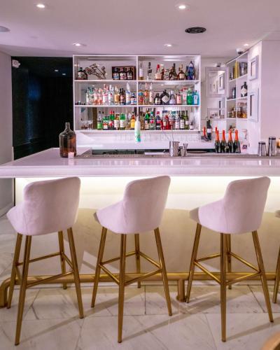 a kitchen with a bar with four white bar stools at Umbral, Curio Collection By Hilton in Mexico City