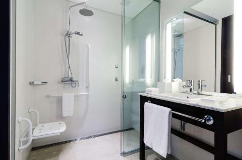 een badkamer met een glazen douche en een wastafel bij Hampton By Hilton Montevideo Carrasco in Montevideo