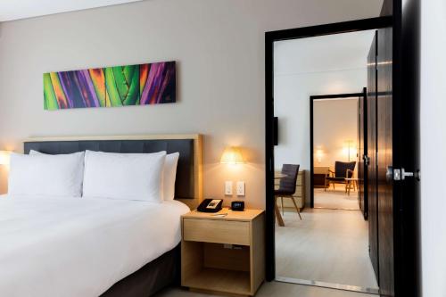 a bedroom with a bed and a door leading into a room at Hilton Garden Inn Merida in Mérida