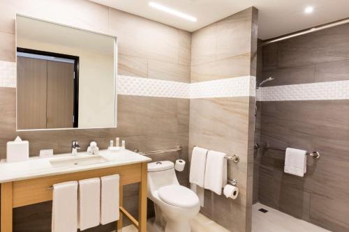 a bathroom with a toilet and a sink and a shower at Hilton Garden Inn Merida in Mérida