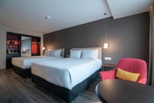 Cette chambre d'hôtel comprend deux lits, une table et des chaises. dans l'établissement Soro Montevideo, Curio Collection By Hilton, à Montevideo