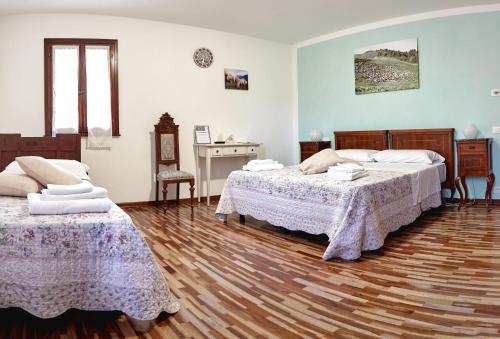 a bedroom with two beds and a wooden floor at Agriturismo La Foscarina in Vescovana