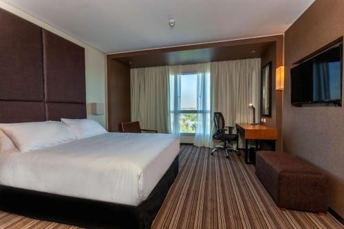 een hotelkamer met een bed, een bureau en een televisie bij Hilton Garden Inn Neuquen in Neuquén