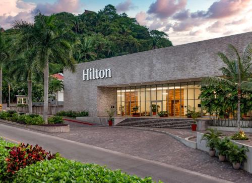 un bâtiment hilton avec des palmiers devant lui dans l'établissement Hilton Vallarta Riviera All-Inclusive Resort,Puerto Vallarta, à Puerto Vallarta