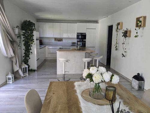 een keuken met een tafel met een vaas met bloemen erop bij La Villa Blanca Montpellier Piscine & proximité Mer in Saint-Jean-de-Védas