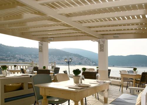a patio with tables and chairs and a view of the water at Skopelos Village Hotel in Skopelos Town