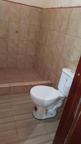a white toilet in a bathroom with a tub at Candurumy Lodge in Tena