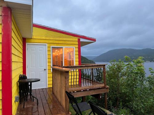 een kleurrijk huis met een terras met een tafel en stoelen bij Knotty Pine Ocean Front Cabin - Adults Only in Ingonish Beach