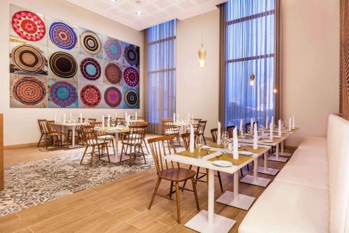 a dining room with tables and chairs and large windows at Hilton Garden Inn Santa Marta in Santa Marta
