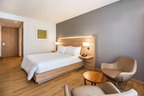 a hotel room with a bed and a chair at Hilton Garden Inn Santa Marta in Santa Marta
