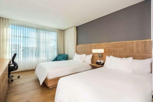 a hotel room with two beds and a window at Hilton Garden Inn Santa Marta in Santa Marta