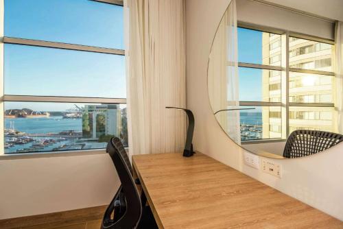 a room with a window with a chair and a mirror at Hilton Garden Inn Santa Marta in Santa Marta