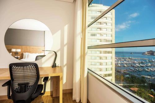 a hotel room with a desk and a window at Hilton Garden Inn Santa Marta in Santa Marta