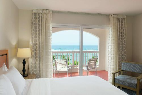 a bedroom with a bed and a balcony with the ocean at Embassy Suites by Hilton Dorado del Mar Beach Resort in Dorado