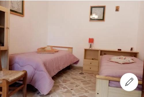 a bedroom with two beds and a chair at Casa Vicolo Urbano in Pollina