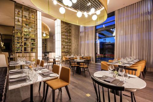 a restaurant with tables and chairs and a large chandelier at Hilton Bogota Corferias in Bogotá