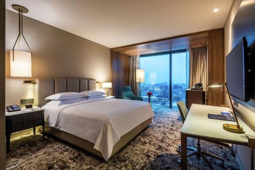 a hotel room with a bed and a desk and a window at Hilton Bogota Corferias in Bogotá