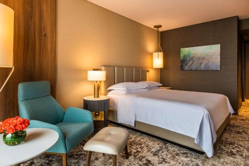 a hotel room with a bed and two chairs and a table at Hilton Bogota Corferias in Bogotá