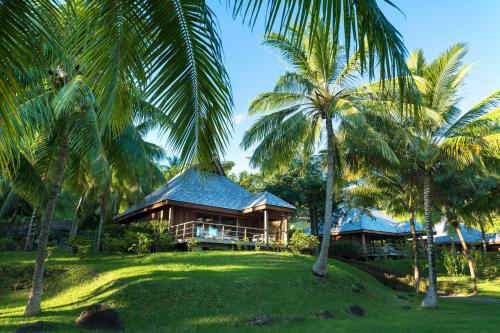 a house with palm trees in front of it at Conrad Bora Bora Nui in Bora Bora