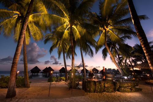 a group of palm trees on the beach at night at Conrad Bora Bora Nui in Bora Bora