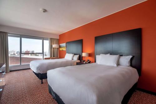 two beds in a hotel room with an orange wall at Hilton Garden Inn Montevideo in Montevideo